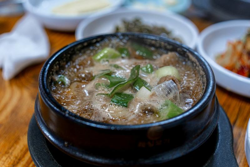 검은 뚝배기에서 끓고 있는 맑은 국물 찌개